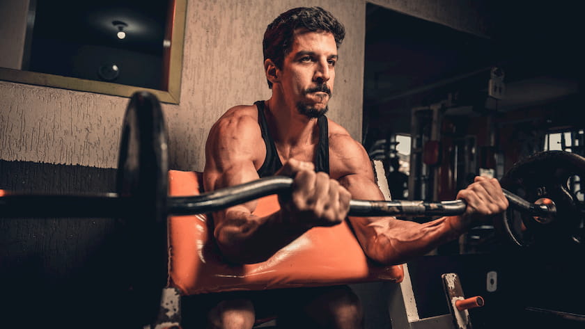 athlete doing EZ bar preacher curls