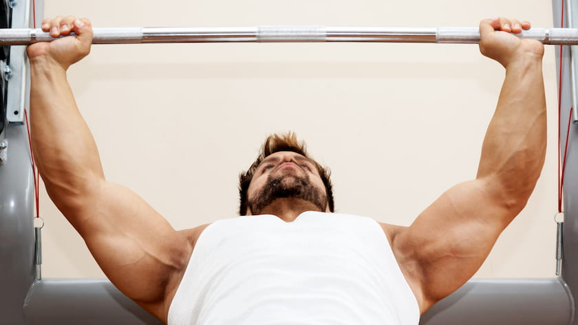 man in white tank top bench press